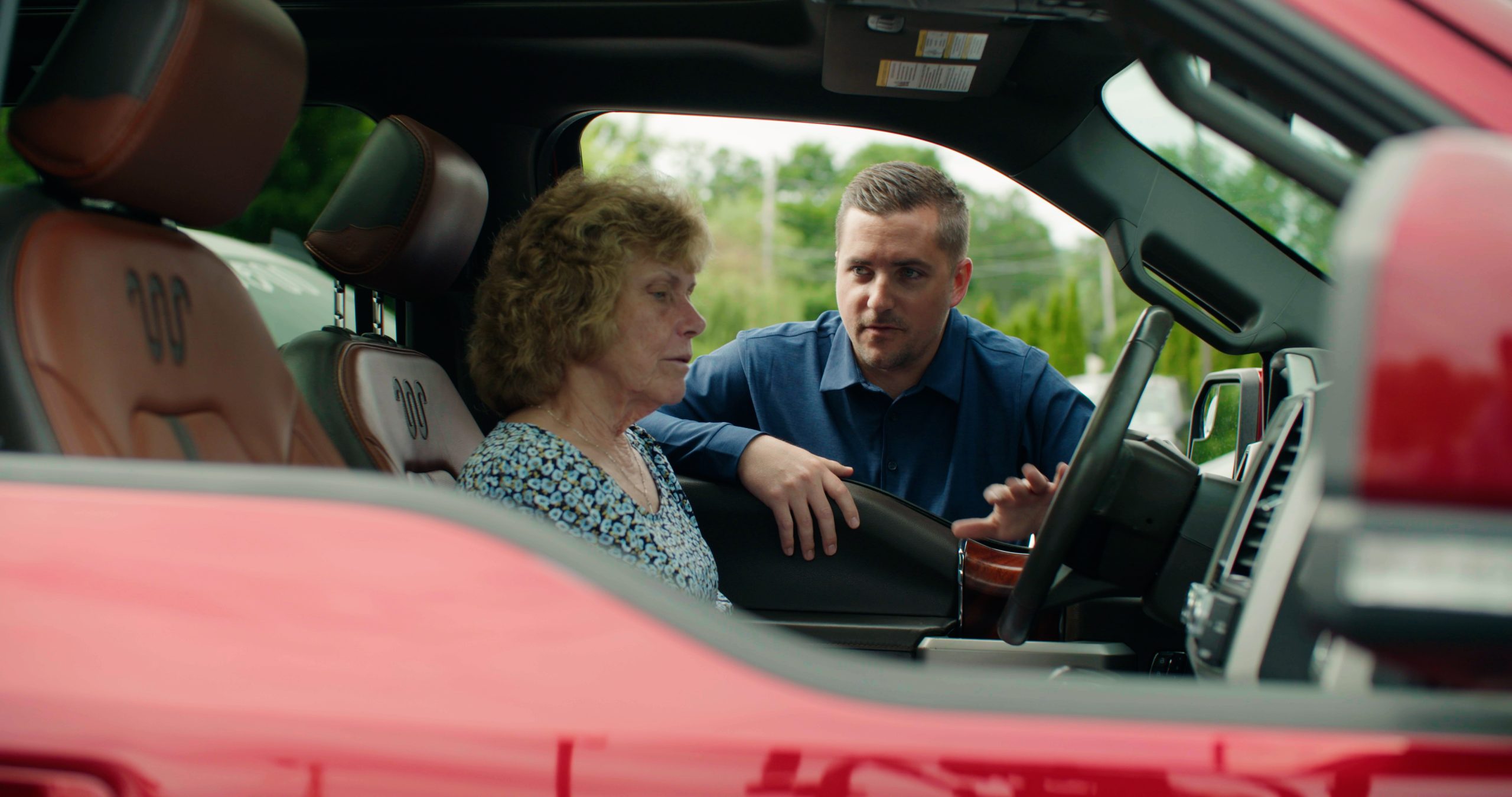 Car Salesman talking to woman in vehicle